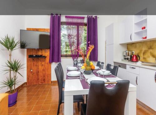 a dining room with a white table and purple curtains at Apartman Ana in Draga Bašćanska
