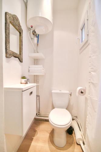 La salle de bains blanche est pourvue de toilettes et d'un miroir. dans l'établissement Au coeur de Sanary-sur-Mer studio cosy, à Sanary-sur-Mer