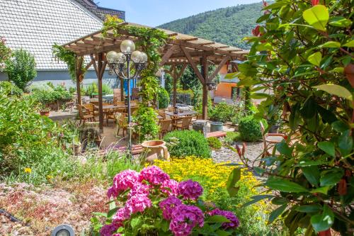 einen Garten mit Blumen und einer hölzernen Pergola in der Unterkunft Weinhotel Hubertus Garni in Klotten