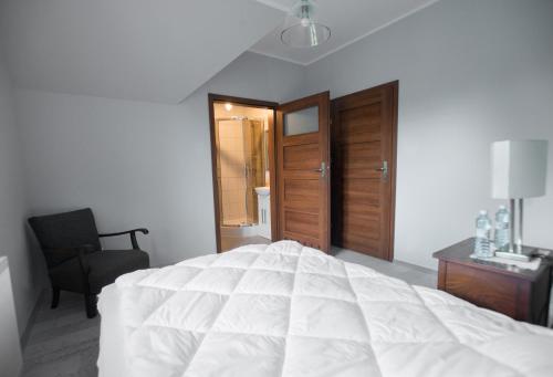 1 dormitorio con 1 cama blanca y 1 silla en Pensjonat w Sam Las, en Barnówko