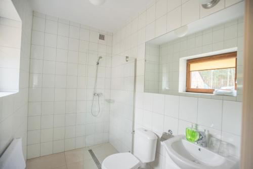 a white bathroom with a toilet and a sink at Pensjonat w Sam Las in Barnówko