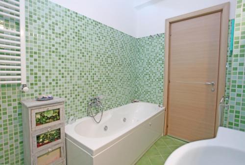 La salle de bains est pourvue de carrelage vert, d'une baignoire et de toilettes. dans l'établissement Casa Stella del Mattino, à Taormine