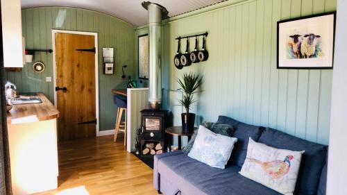 a living room with a blue couch and a stove at Mid Wales Luxury Huts in Darowen