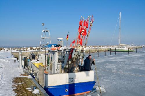 a man is standing on a boat in the snow at Meerforelle 207 - Villa Seeblick in Sassnitz