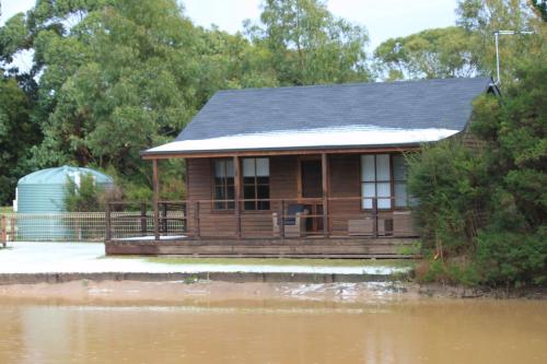 a house on a dock next to a body of water at Inverloch par 3 Golf & Cafe and Cocoa & Briar Cottages in Inverloch
