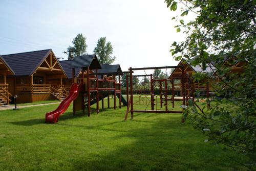 un parque infantil con un tobogán en el césped en Domki i pokoje "ZIELONA PRZYSTAŃ" en Sztutowo
