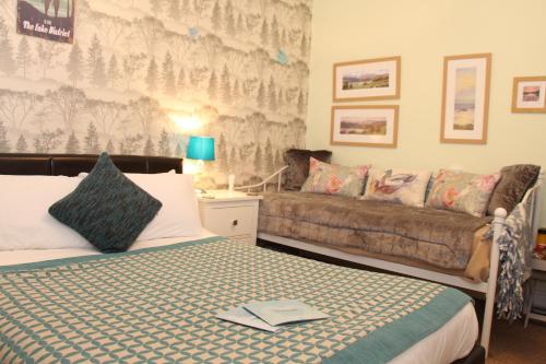 a bedroom with a bed and a couch at Invergarry Room Only Guest House For Adults in Windermere