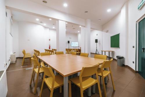 a conference room with a wooden table and yellow chairs at Open011 in Turin