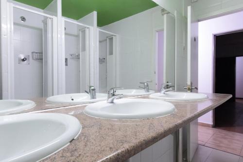 a bathroom with four sinks and three mirrors at Diagonal House Hostel in Barcelona