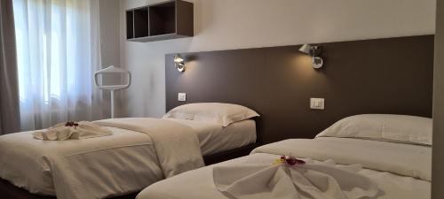 two beds in a hotel room with white sheets at RivAppartamenti in Riva del Garda
