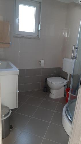 a bathroom with a toilet and a sink and a window at Holiday House Romi in Pula