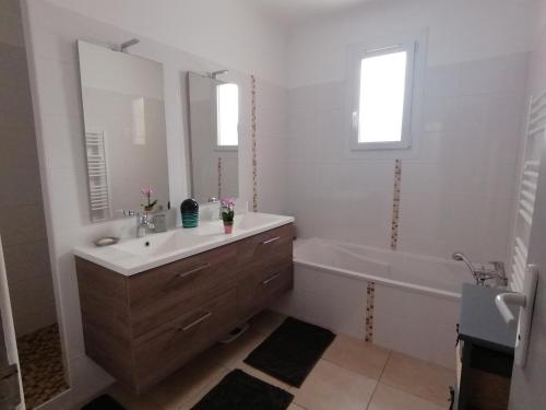 a white bathroom with a sink and a tub and a mirror at Chez Titi in Mornas