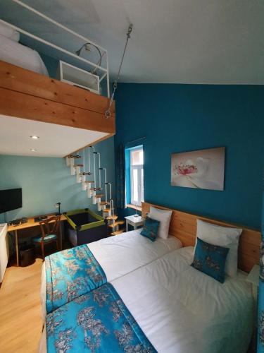 a bedroom with a large bed and a blue wall at La Fête au Palais in Lustin