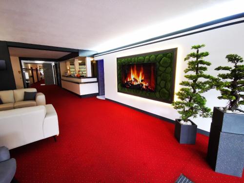 a living room with a fireplace and a red carpet at Hotel Grille in Erlangen