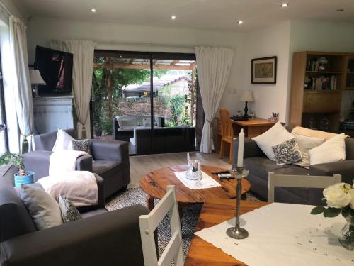 uma sala de estar com sofás e uma mesa em Waybury Cottage - a cozy home from home ! em Joanesburgo