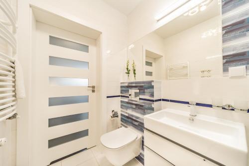 a white bathroom with a toilet and a sink at KASANDRA in Pobierowo