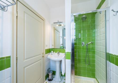 a bathroom with a sink and a shower with green tiles at Relais Paradiso Resort & Spa in Gualdo Cattaneo