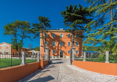 an orange building with a fence and trees at Relais Paradiso Resort & Spa in Gualdo Cattaneo