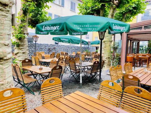 an outdoor restaurant with tables and chairs and an umbrella at Gasthof Rebstock in Friedrichshafen