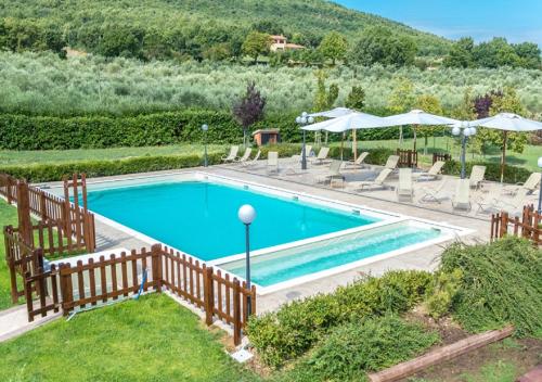 a pool with chairs and umbrellas in a yard at Relais Paradiso Resort & Spa in Gualdo Cattaneo