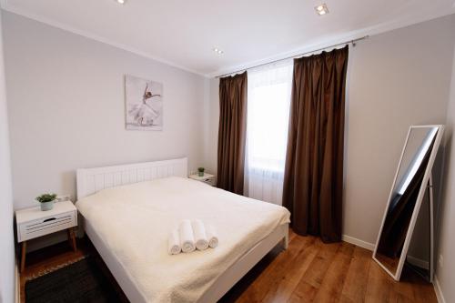 1 dormitorio con 1 cama con sábanas blancas y ventana en Комфортна та тиха квартира у Центрі міста, en Ternopilʼ