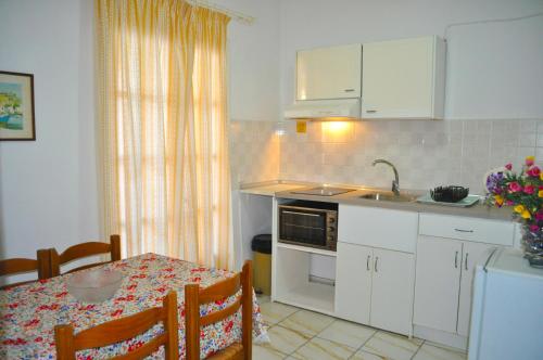a kitchen with white cabinets and a table and a sink at Holiday Apartments Maria with Pool and Panorama View - Agios Gordios Beach in Agios Gordios