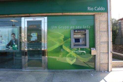 un edificio verde con una puerta giratoria y un teléfono público en Cantinho Verde T3, en Gerês