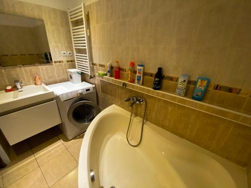 a bathroom with a tub and a sink and a washing machine at 3 Bedroom apartment in the part of the city in Banská Bystrica