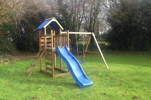 a playground with a blue slide and a swing at The Bakery in Beauficel