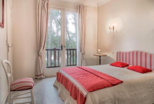 a bedroom with a bed with red pillows and a window at Villa Le Menez Avec Vue Sur Le Lac Marin Pour 10 Personnes in Hossegor
