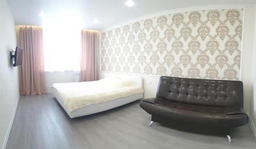 ヤロスラヴリにあるApartment on 8 Marta 17Aのベッドルーム1室(ベッド1台、黒い革張りの椅子付)