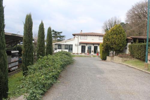 a road in front of a white house with trees at Hotel Il Casale in Trevignano Romano