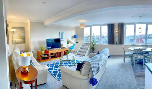 a living room with white furniture and a dining room at Superb Scarborough Penthouse with Balcony, lift, parking, views in Scarborough