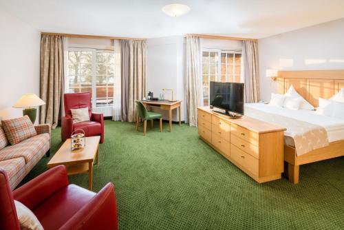 a hotel room with a bed and a tv at Romantik Hotel Jagdhaus Eiden am See in Bad Zwischenahn