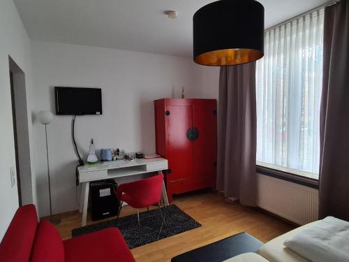 a living room with a red cabinet and a desk at Hotel Aleo in Bochum