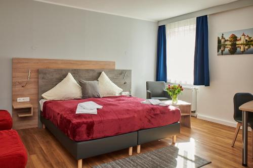 a bedroom with a red bed with a red blanket at Zur Allacher Mühle in Munich