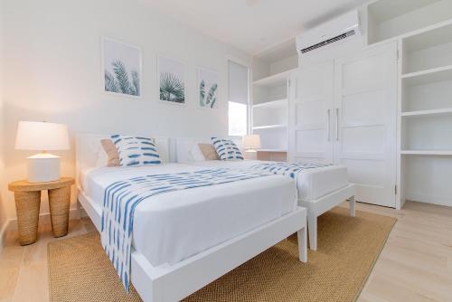 a white bedroom with a bed with blue and white sheets at Garden Grove in Saint James