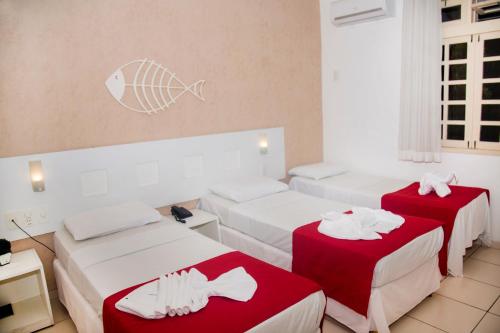 two beds in a room with red and white sheets at Pousada Pérola Dourada Maceio in Maceió