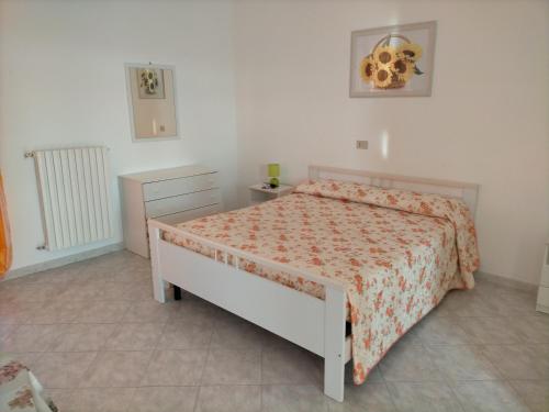 um quarto branco com uma cama com colcha floral em Appartamenti vista mare, em Peschici
