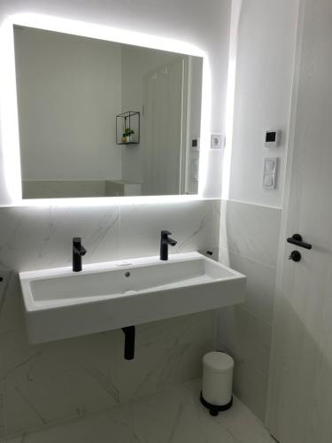 a white bathroom with a sink and a mirror at OpusTisza7 Apartman in Tiszafüred