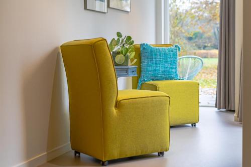 two yellow chairs in a room with a window at Villa de Hazelaar in Schoorl
