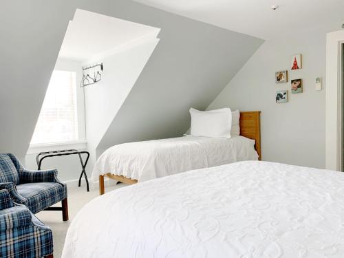 a bedroom with two beds and a chair at The Inn at Manchester in Manchester