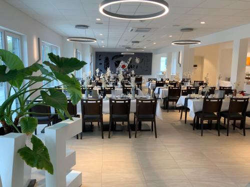 un salón de banquetes con mesas, sillas y plantas en RheinVilla ARTE, en Remagen