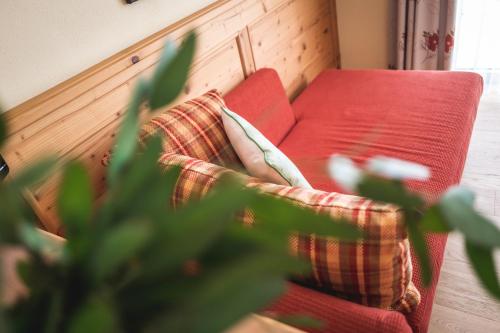 a red couch with two pillows on it at Hotel Natur-Landhaus Krone in Maierhöfen