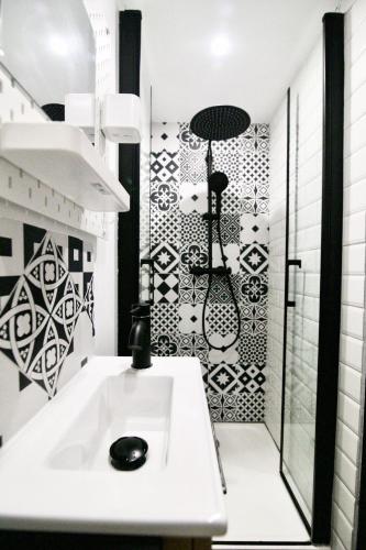 La salle de bains est pourvue d'un lavabo blanc et de carrelage noir et blanc. dans l'établissement Studio-résidence front de mer ⎮ parking gratuit, à Bandol