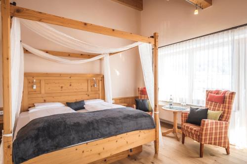 a bedroom with a canopy bed and a chair at Hotel Natur-Landhaus Krone in Maierhöfen