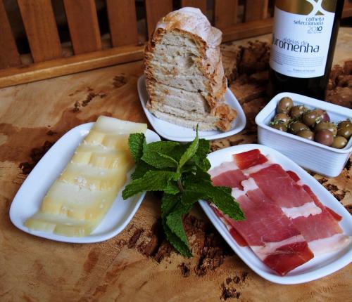 a table with plates of cheese and bread and a bottle of wine at Casas de Campo do Castro da Cola in Marchicão