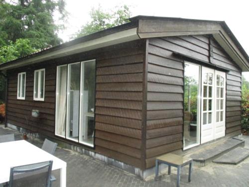 a small wooden cabin with a table and chairs at Midden in de natuur, een ruim chalet aan de rand van het bos, nr 30 in Marum
