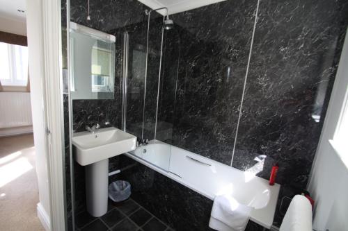 a black tiled bathroom with a sink and a mirror at Links Country Park Hotel in Cromer
