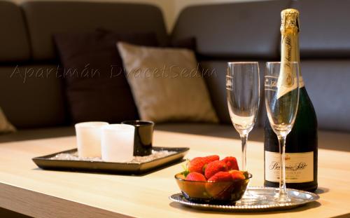 a table with a bottle of champagne and a bowl of strawberries at Apartman DvacetSedm in Lipno nad Vltavou